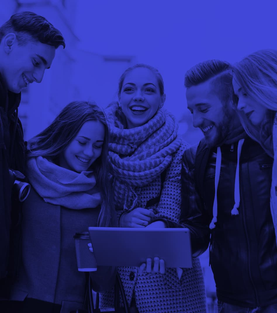A group of five young people standing outdoors, smiling and looking at a tablet together. The image is overlaid with a blue color filter.